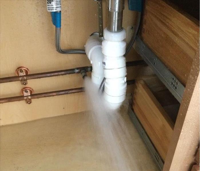water bursting from pipe under sink.